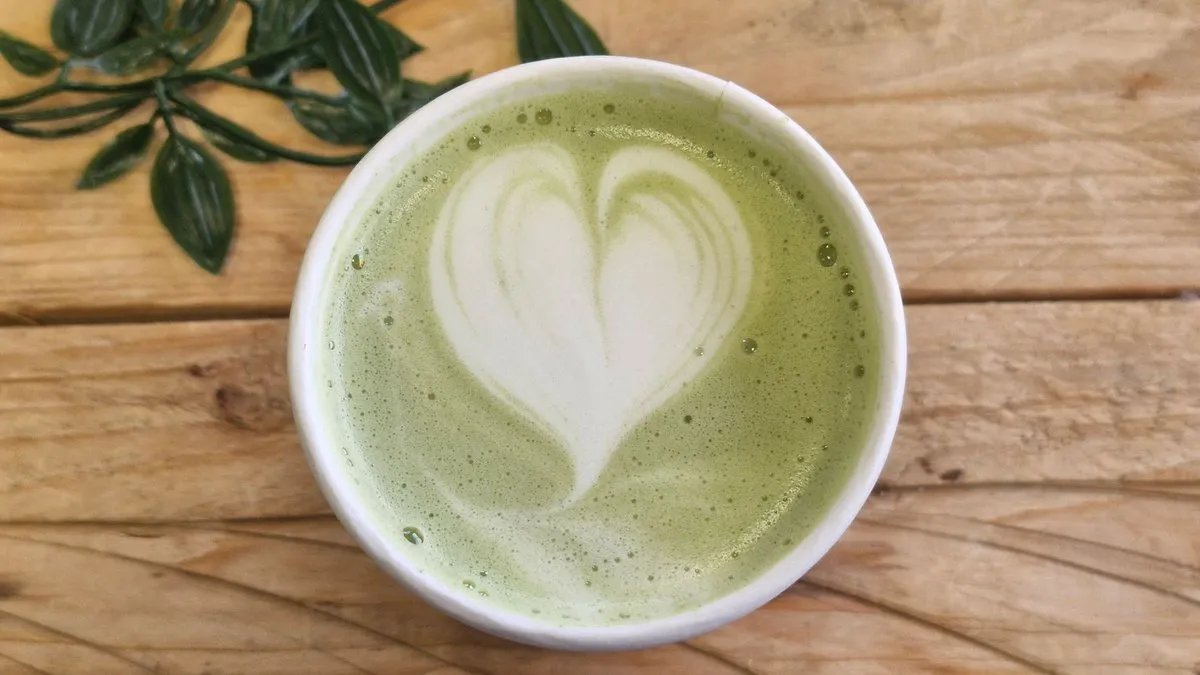 Tasse de matcha latte avec un cœur en mousse de lait, vue de dessus sur une table en bois