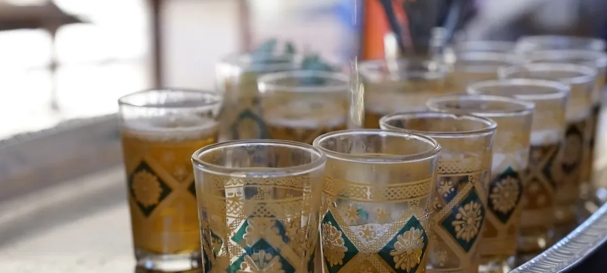 Thé à la menthe versé de haut dans des verres marocains décorés sur un plateau argenté