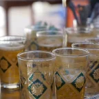 Thé à la menthe versé de haut dans des verres marocains décorés sur un plateau argenté