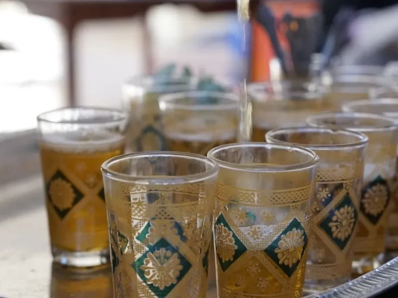 Thé à la menthe versé de haut dans des verres marocains décorés sur un plateau argenté