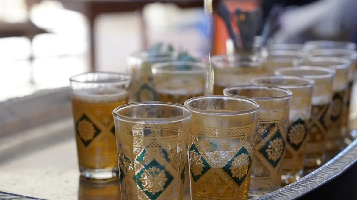 Thé à la menthe versé de haut dans des verres marocains décorés sur un plateau argenté